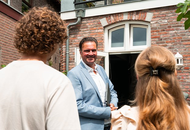 De makelaar leidt een stel rond in een huis die bij hen te koop staat