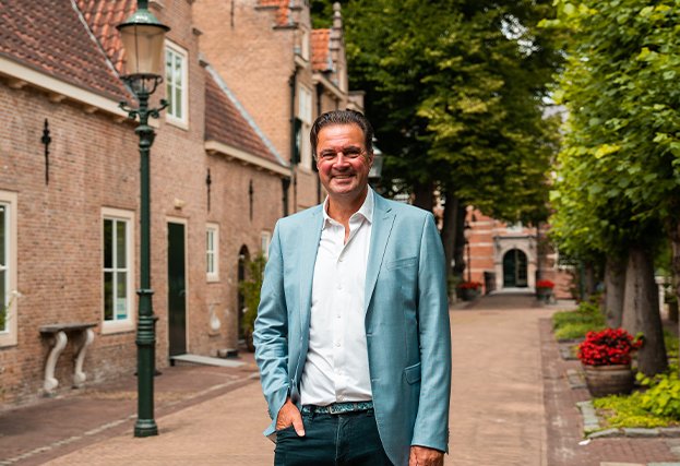 Makelaar van Bink en Partners in een historische straat met bakstenen gevels en bomen