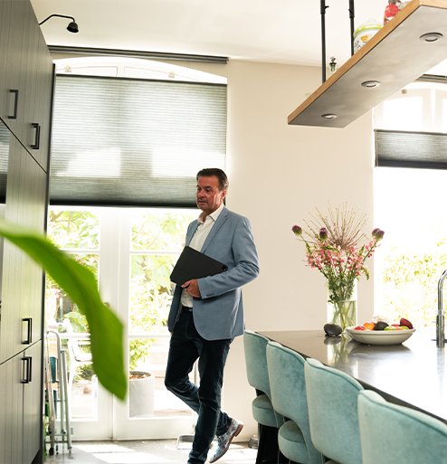Makelaar van Bink en Partners loopt door een moderne keuken tijdens een woninginspectie