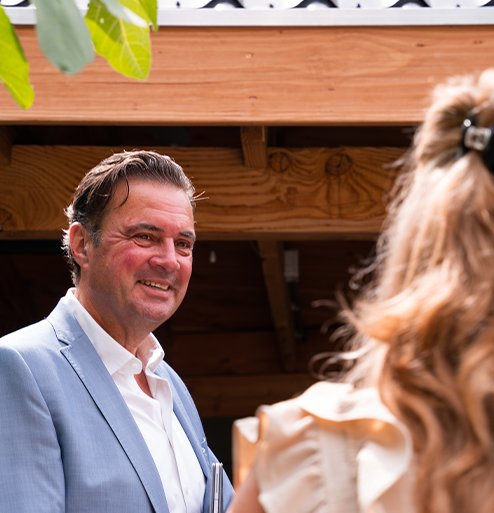 Makelaar van Bink en Partners in gesprek met klant in een tuinomgeving