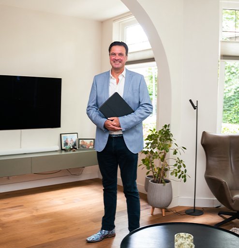 Makelaar van Bink en Partners staand in een ruime woonkamer met grote ramen